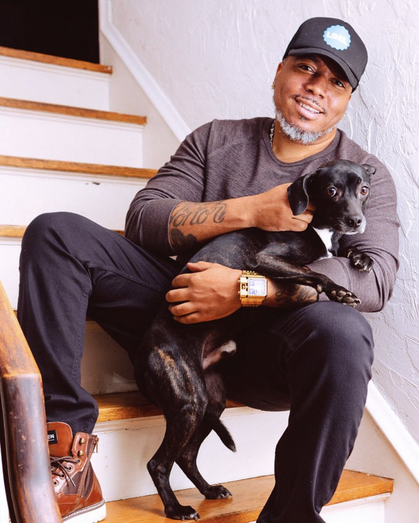 Jay.R Fogle seated at home holding a black puppy